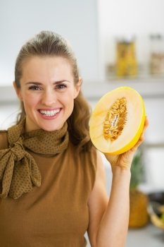 Happy young housewife holding melon slice