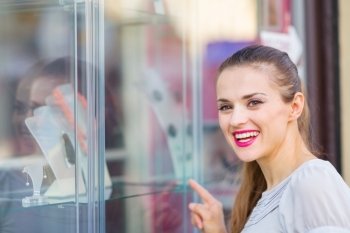 Smiling woman pointing on showcase