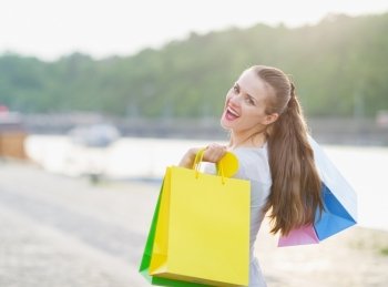 Smiling woman with shopping bags walking embankment