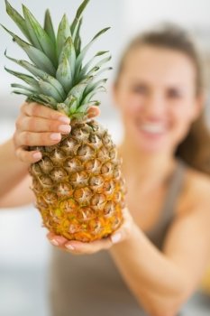 Closeup on pineapple in hand of happy young woman