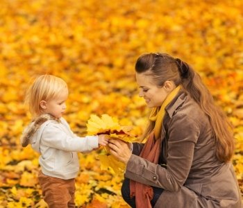 Young mother showing baby fallen leaves