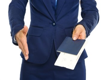 Closeup on business woman giving passport with air tickets and stretching hand for handshake