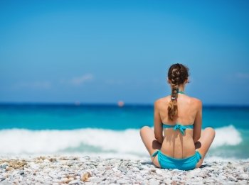 Woman sitting on beach. Rear view