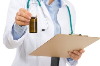 Closeup on medical doctor woman with clipboard and medecine bottle