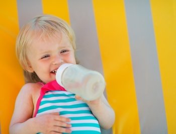 Portrait of happy baby laying on sunbed and drinking water