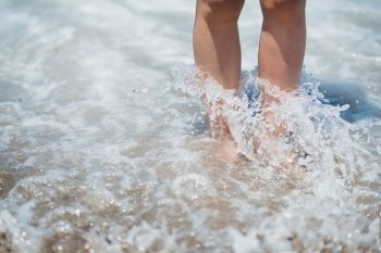Closeup on legs in sea wave splashes