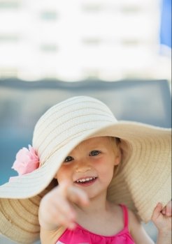 Portrait of baby in beach hat pointing in camera