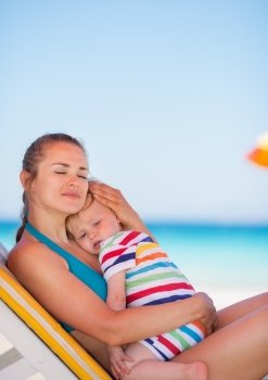 Mother and baby relaxing on sunbed on beach