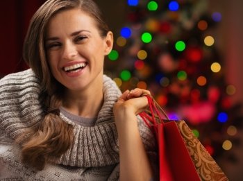 Happy woman with shopping bag in front of Christmas lights