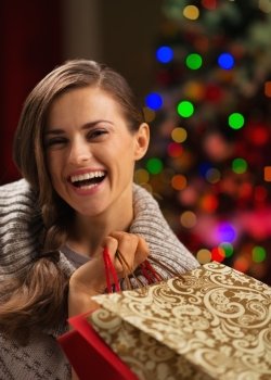 Smiling woman with shopping bag in front of Christmas lights