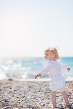 Baby walking on beach and looking on copy space