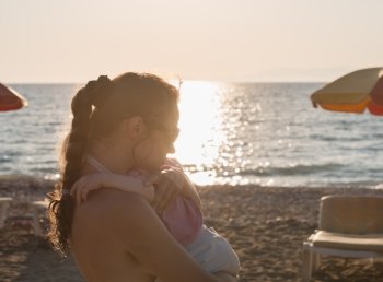 Silhouette of mother hugging baby on lonely beach