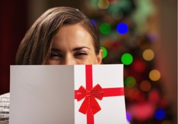 Young woman holding christmas postcard in front of face
