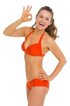 Smiling young woman in swimsuit showing ok gesture