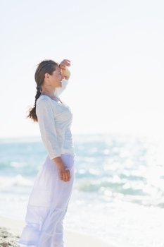 Portrait of happy young woman on sea shore looking into distance