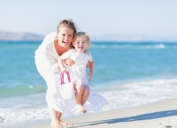 Happy mother and baby on sea shore having fun