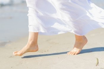 Closeup on leg of young woman on sea coast