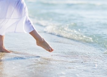 Closeup on leg of young woman standing on sea shore