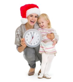 Happy mother in Christmas hat and baby girl holding clock