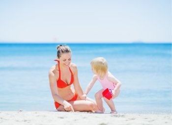 Happy mother and baby playing on beach