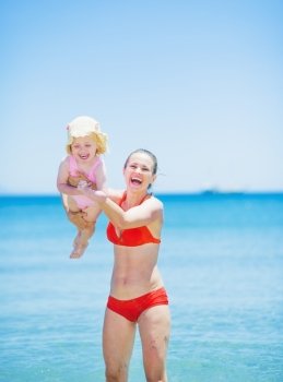 Happy mother playing with baby on beach