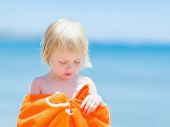 Portrait of baby wrapped in towel on beach