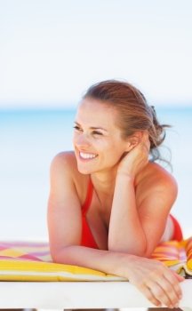 Smiling young woman on beach looking on copy space