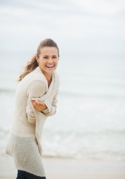 Happy young woman in sweater on coldly beach