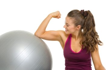 Happy fitness young woman checking biceps