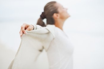 Closeup on hand of young woman in sweater on lonely beach