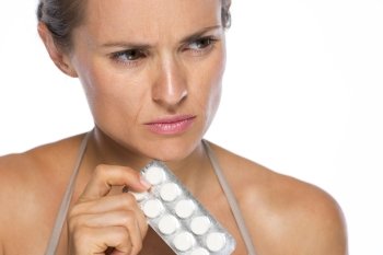 Closeup on concerned young woman with pack of pills