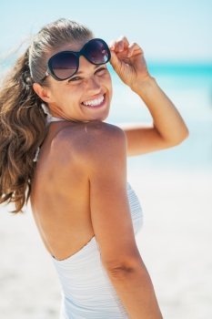 Portrait of smiling young woman in swimsuit with sunglasses on beach