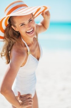 Portrait of smiling young woman in swimsuit and beach hat at seaside
