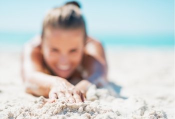 Closeup on happy young woman in swimsuit laying on sandy beach