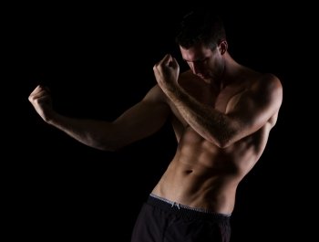Muscular man in attack pose on black