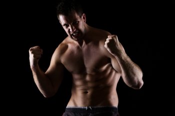 Angry athletic man in attack pose on black