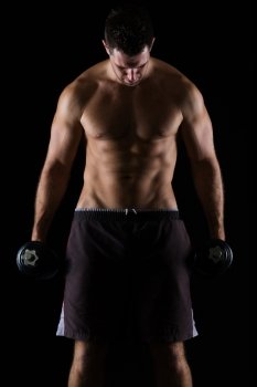 Strong male athlete holding dumbbell on black
