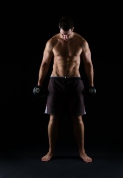 Strong muscular man holding dumbbell on black