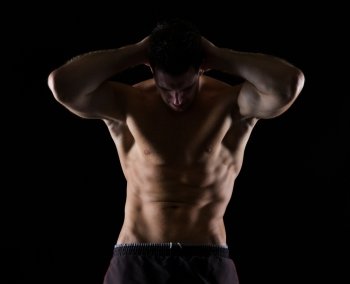Strong male athlete posing on black