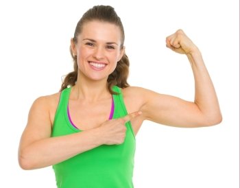 Happy fitness young woman pointing on biceps