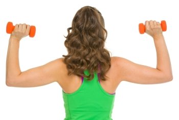 Slim woman making exercise with dumbbells . rear view