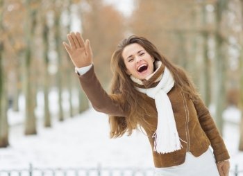 Happy young woman in winter jacket saluting outdoors