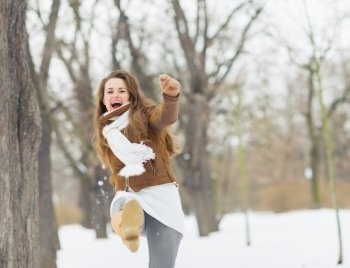Happy young woman hitting snow with leg