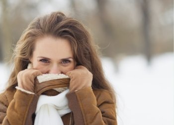 Young woman hiding in winter jacket outdoors