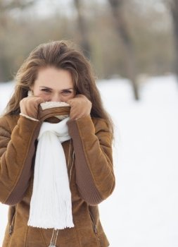 Young woman hiding in winter jacket outdoors