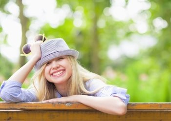 Smiling hipster girl sitting on bench in the park