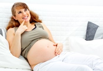 Dreams  beautiful pregnant woman sitting on sofa at home and holding her belly
