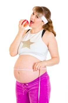 Smiling beautiful pregnant woman holding measure tape and  eating apple isolated on white
