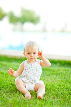 Portrait of adorable baby sitting on grass
