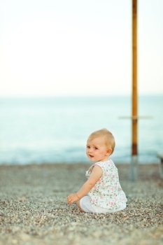Baby sitting on beach and looking back